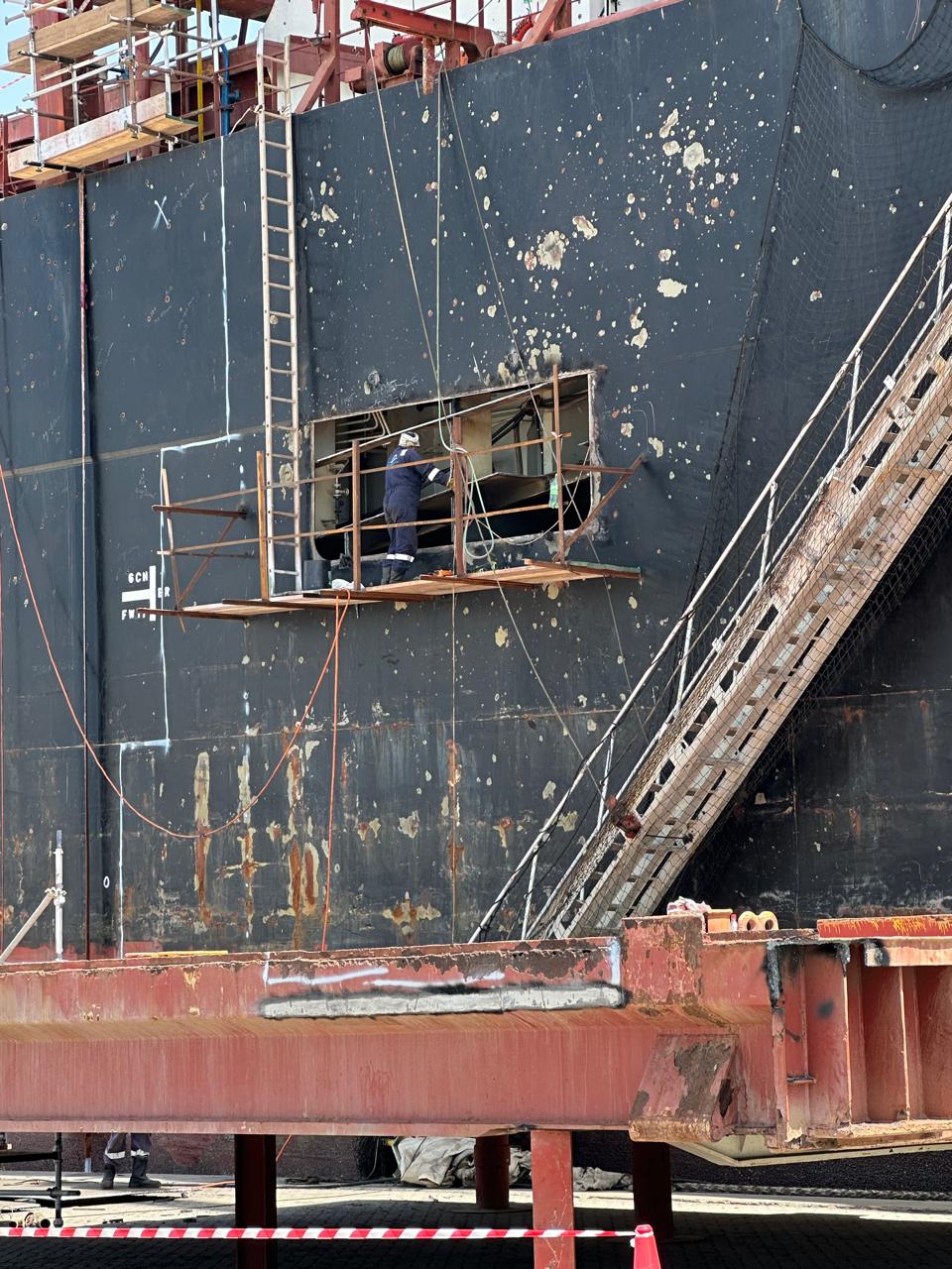 Engineer performing hull repair work on staging in dry dock