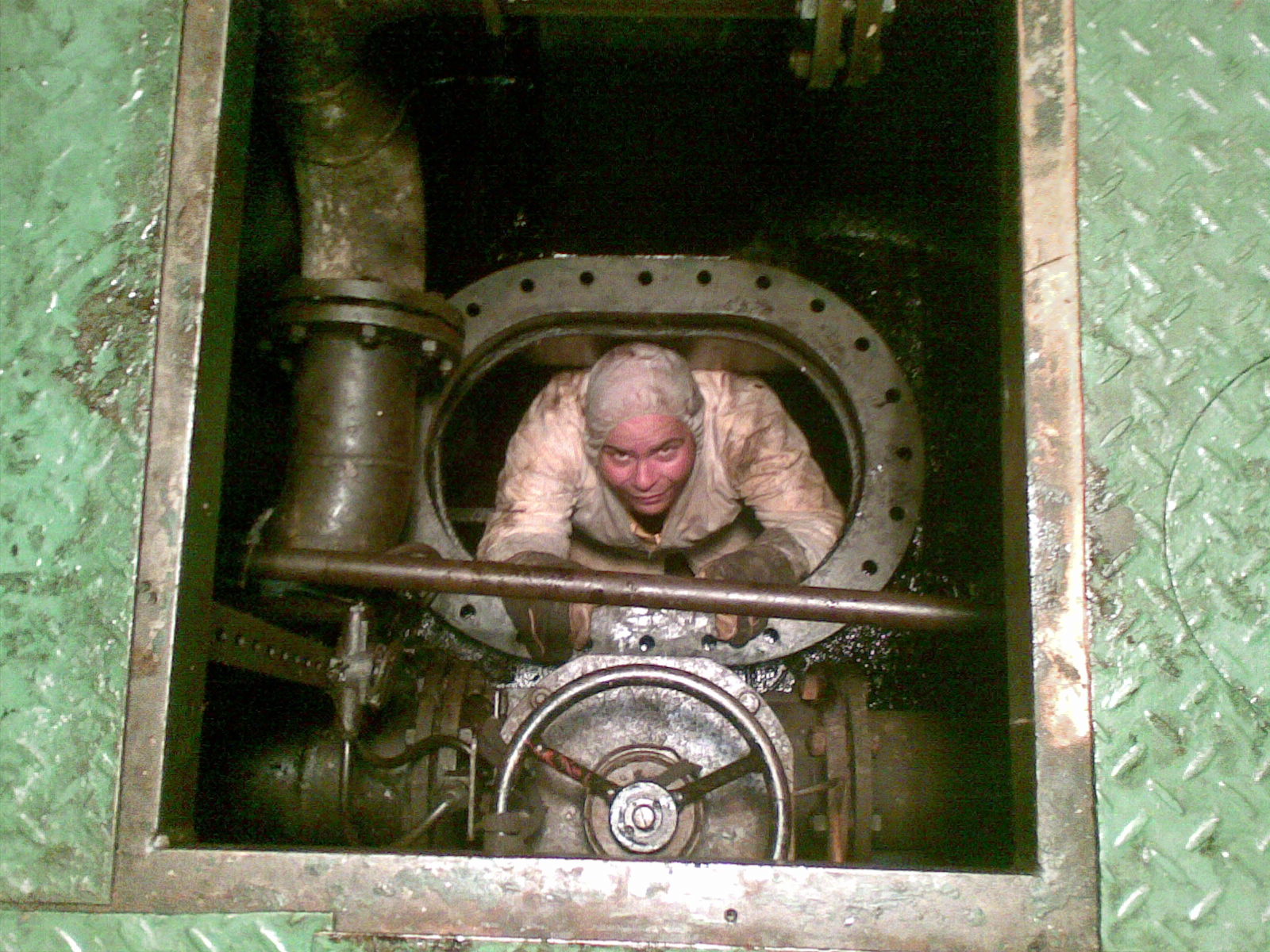 Engineer entering main engine crankcase through inspection door for survey