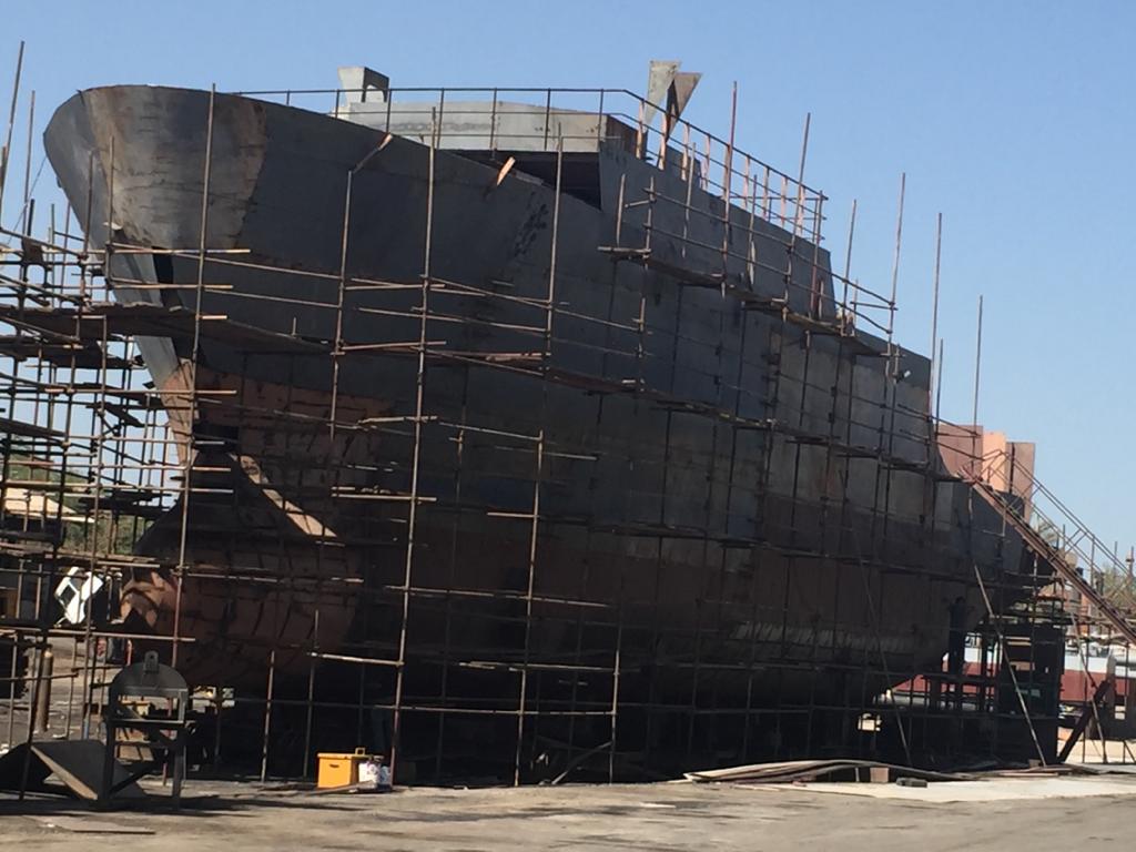Vessel hull under construction with scaffolding at shipyard