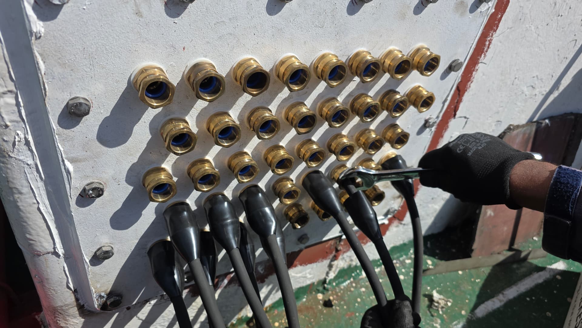 Brass cable gland transit sealing high-voltage cables at bulkhead penetration
