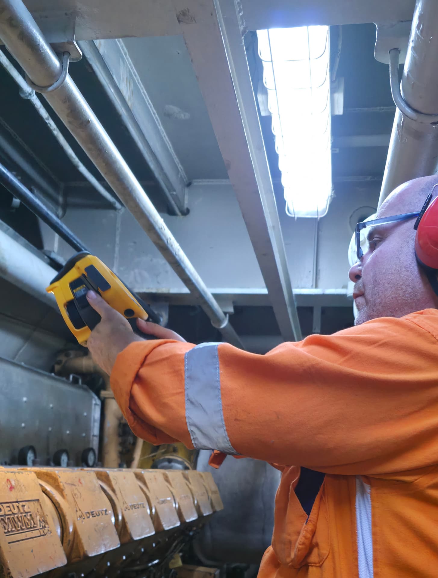 Engineer performing thermal imaging survey on a marine engine
